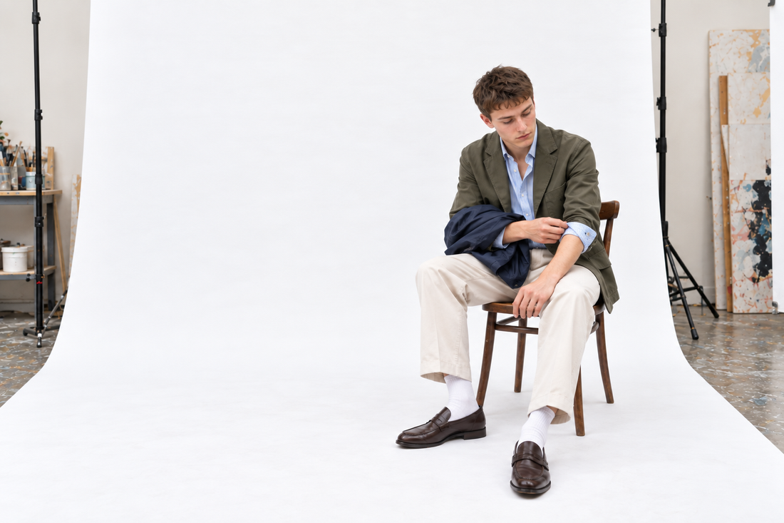 Olive cotton jacket, striped shirt, stone trousers and brown loafers with a light rain layer