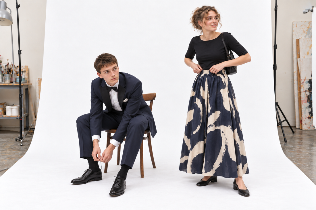 Woman checking a printed evening skirt beside a man tying his dress shoes in a midnight-blue dinner suit.
