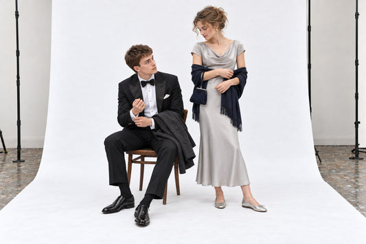 Woman in a pearl-grey evening dress, navy wrap and silver flats beside a man in a black dinner suit.