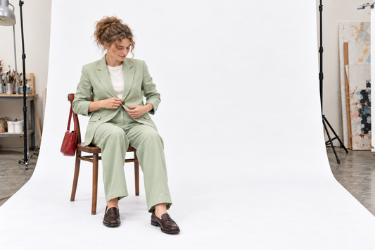 Pale green summer trouser suit with an ivory top, dark brown loafers and a small red bag, checked for seated comfort.