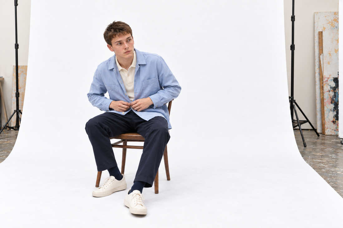 Cream polo and navy trousers layered with a roomy pale blue cotton overshirt.