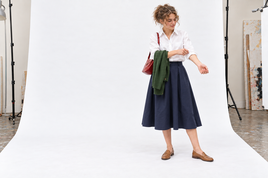 White cotton shirt and navy A-line skirt with tan flats and a removable fine cardigan.